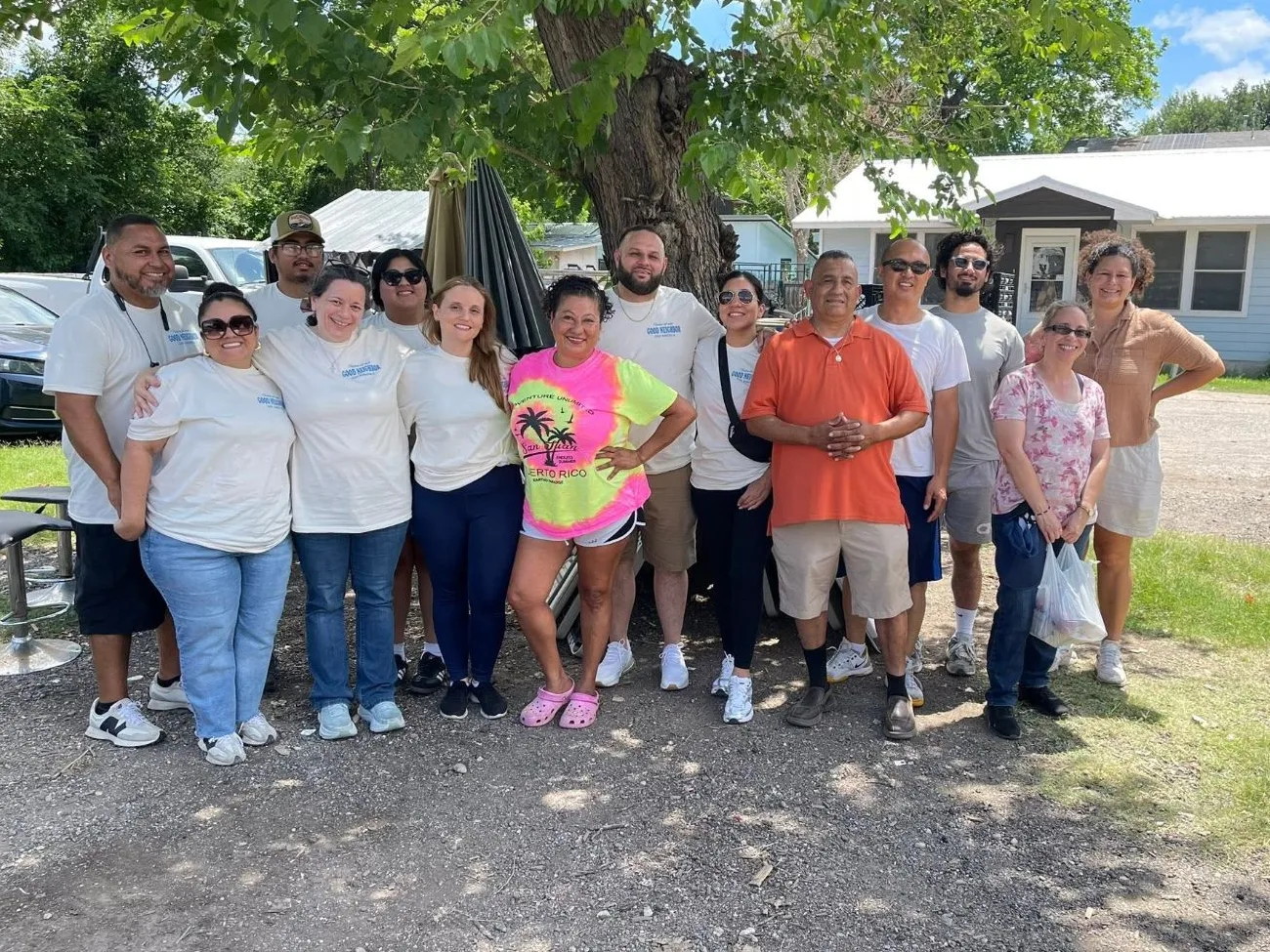 A volunteer team in matching shirts with neighbors outside the Mobile Blessings pantry